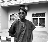 Black-and-white photo of Saviour Inyang standing outside a building