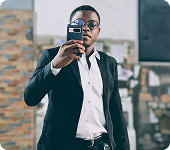 Saviour Inyang in a suit, taking a mirror photo with a phone